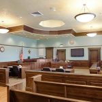 Empty courtroom with wooden benches and American flag.