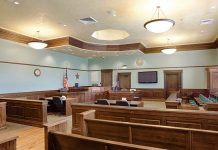 Empty courtroom with wooden benches and American flag.