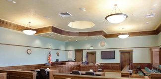 Empty courtroom with wooden benches and American flag.