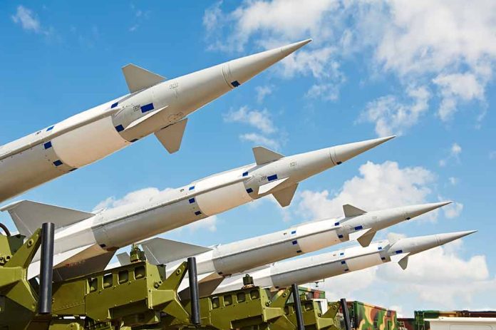 Multiple missiles pointed upward on launchers against blue sky.