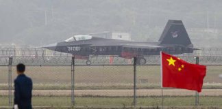 Jet with "31001" marking behind barbed wire fence.