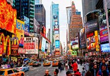 Times Square crowded with people and bright electronic advertisements.