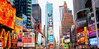 Times Square crowded with people and bright electronic advertisements.