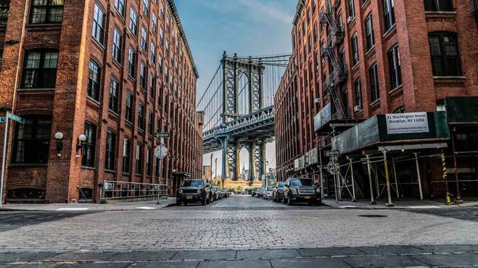 Street view with bridge between two brick buildings.