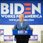 Man at podium with Biden campaign signs behind him.