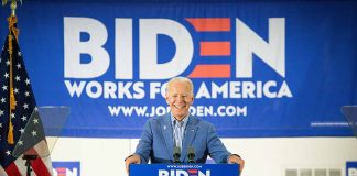 Man at podium with Biden campaign signs behind him.