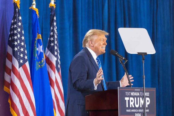 Person speaking at podium with flags in background.