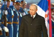 A man in dark coat at a military event.