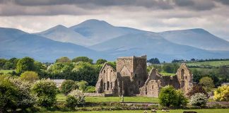 Ruins, sheep grazing, mountains and cloudy sky.