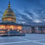 Capitol building illuminated against evening sky.