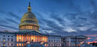 Capitol building illuminated against evening sky.