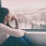 Person sitting and looking out a window at snow