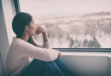 Person sitting and looking out a window at snow