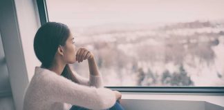 Person sitting and looking out a window at snow