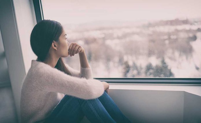 Person sitting and looking out a window at snow