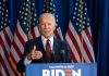 Man speaking at podium with American flags behind.