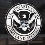 U.S. Department of Homeland Security emblem on wall.