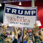 Sign at crowded rally for Trump campaign.