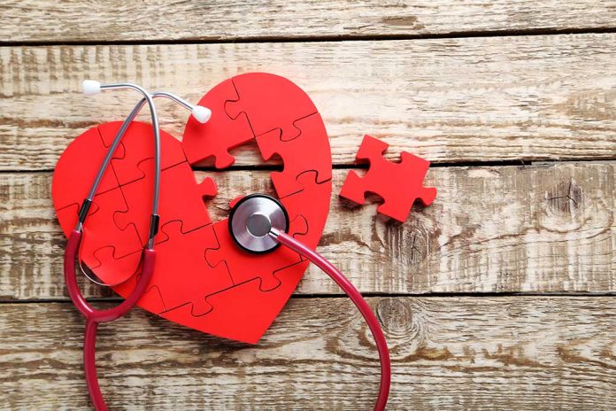 Red heart puzzle with stethoscope on wooden background.