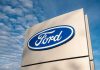 Ford logo sign against blue sky.