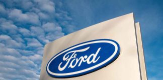 Ford logo sign against blue sky.