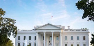 White house with fountain and flags, front view.