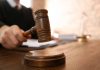 Judge with gavel on wooden desk courtroom setting