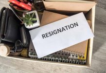 Envelope labeled "RESIGNATION" atop office supplies in box.