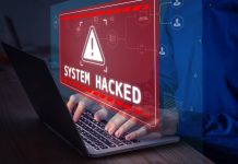 Warning sign "System Hacked" on laptop screen.