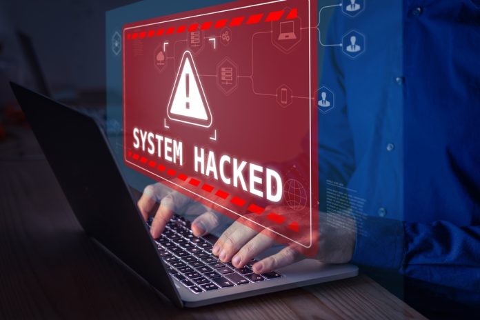 Warning sign "System Hacked" on laptop screen.