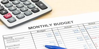 Calculator and pens on monthly budget sheet