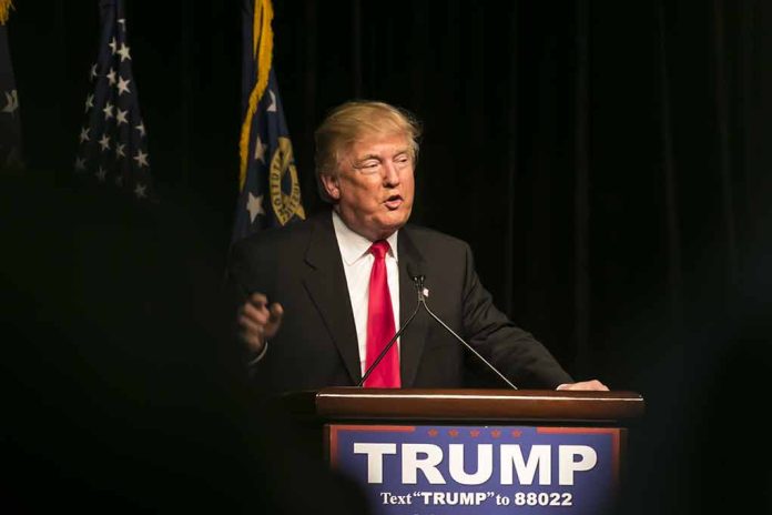 Man speaking at podium with "TRUMP" sign.