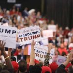 Crowd holding signs supporting Trump at rally.