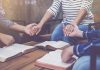 People holding hands in prayer with open books