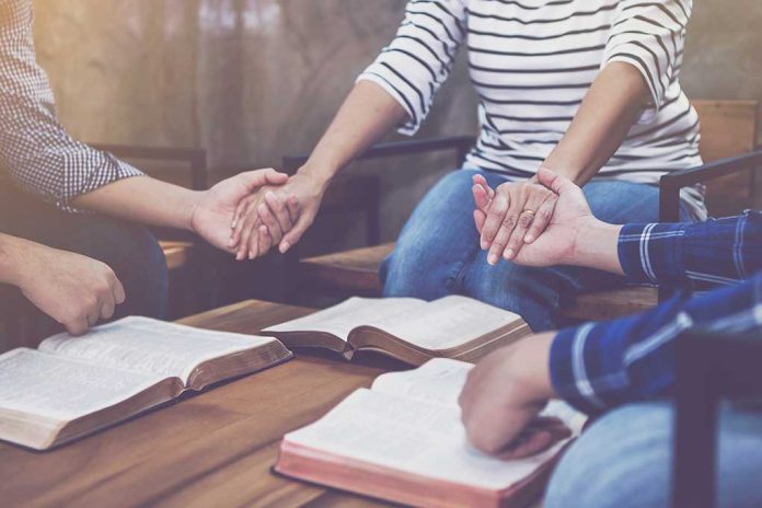 People holding hands in prayer with open books