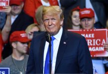 Person at a rally with Make America Great Again signs.