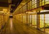 Empty hallway between rows of prison cells.