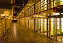 Empty hallway between rows of prison cells.