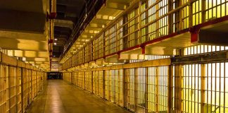 Empty hallway between rows of prison cells.