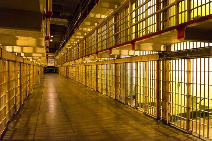 Empty hallway between rows of prison cells.