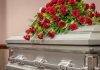 Silver casket with red rose arrangement on top.