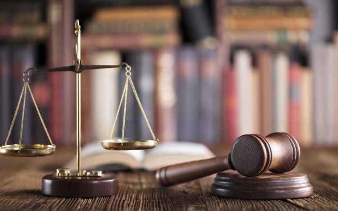 Gavel and scales on desk with books.