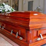 Wooden casket with white flowers in a funeral home.