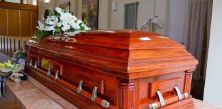 Wooden casket with white flowers in a funeral home.