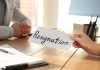 Person handing over resignation letter at a desk.