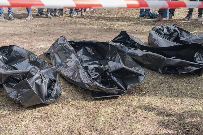 Three black body bags on the ground.