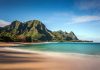 Beach with mountains and clear blue water.