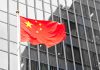 Chinese flag waving in front of glass building