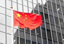 Chinese flag waving in front of glass building