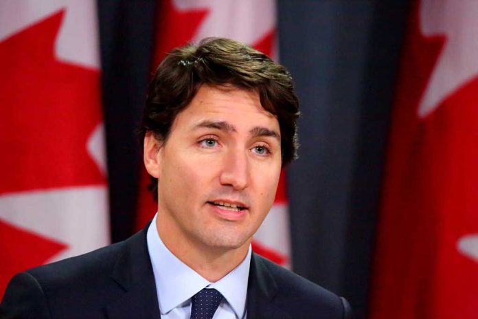 Man speaking in front of Canadian flags.